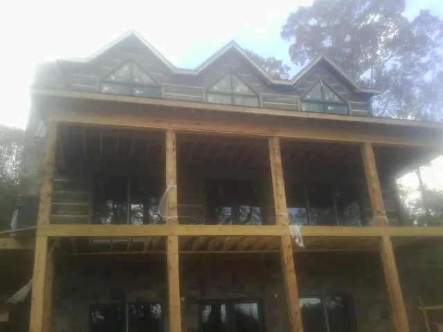 Dormers and porch framing on a large log home under construction — Roof Coating work by our crew in Wilmington