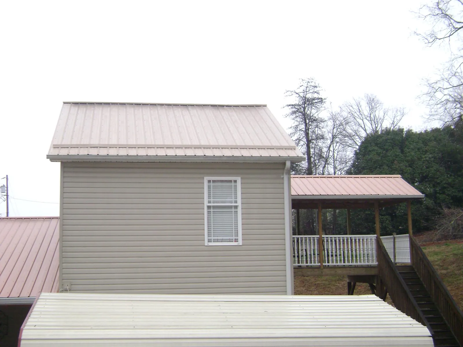 Tan metal roofs on a two story addition and attached porch, from a Roof Replacement job in Wilmington
